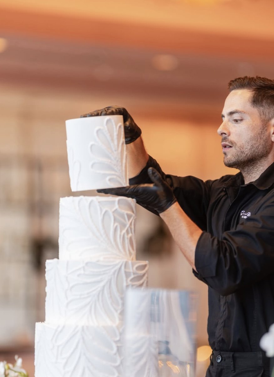 Gabriel Díaz stacking the tiers of a white wedding cake